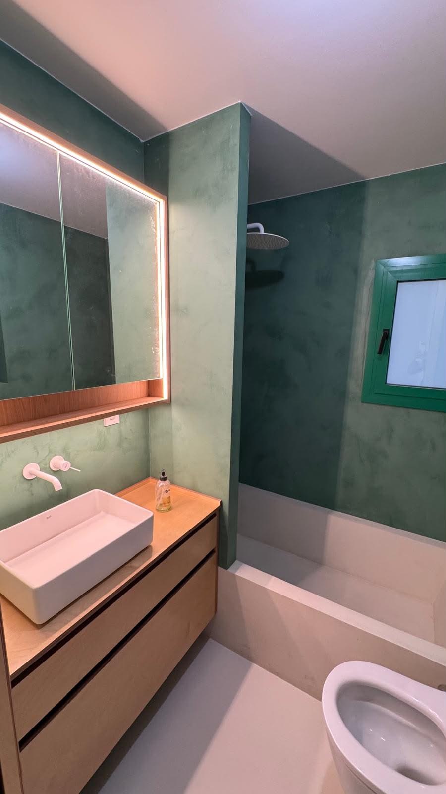 Baño en verde con bañera de obra y mueble de lavabo en madera, reforma VAGAM2000.